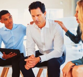 Male employee with mental health problems in divorce, grief or loss with helpful coworkers