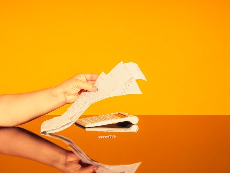 Women's hands with a stack of paid checks. The concept of doing home bookkeeping, keeping track of expenses and income, growing debts, filling out tax returns.