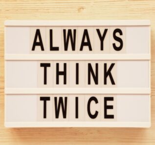 'Always think twice' words on a lightbox on a white wooden surface, top view. Overhead, from above, flat lay.