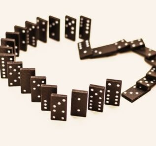 separation or breaking up the love (black dominoes in the form of hearts fall in a Domino effect on white background)