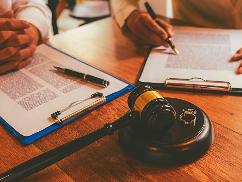Judge gavel with Justice lawyers deciding, consultation on marriage divorce between married couple and signing divorce documents on table. Concepts of Law and Legal services.