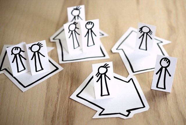 Paper cut of people standing on their own house