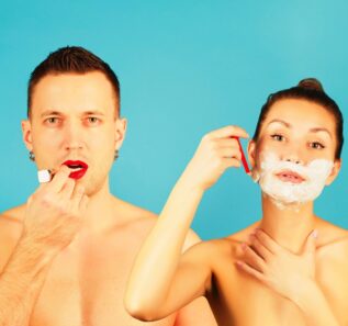 a man paints his lips with red lipstick and a girl shaves her face with a razor with shaving foam on a blue background. Theme of gender, roles in society