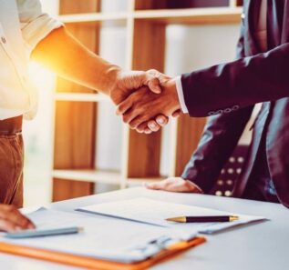 Middle age Asian partner lawyers attorneys shaking hands after discussing a contract agreement done.