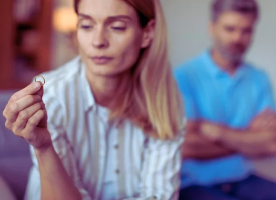 Unhappy adult caucasian wife holding ring and ignoring disappointed man in living room. infidelity influence divorce