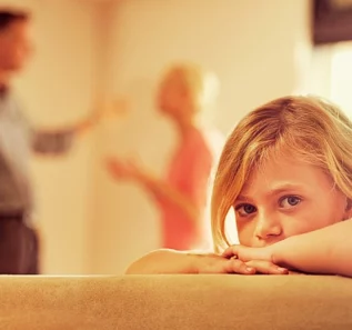 Little girl looking unhappy as her parents argue in the background. First Custody Hearing