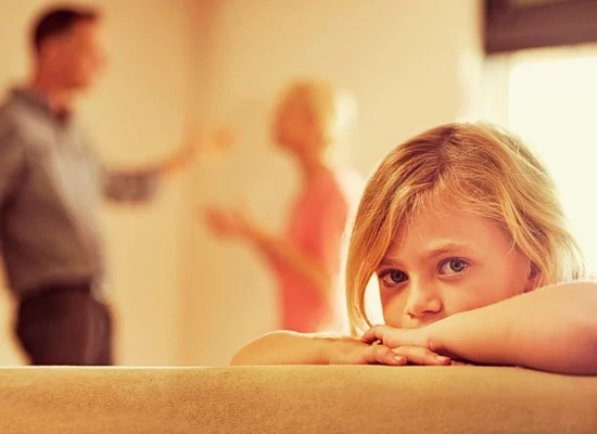 Little girl looking unhappy as her parents argue in the background. First Custody Hearing