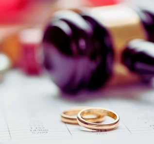 Close up wedding rings with wooden gavel in the background. When an Uncontested Divorce Turns Contested
